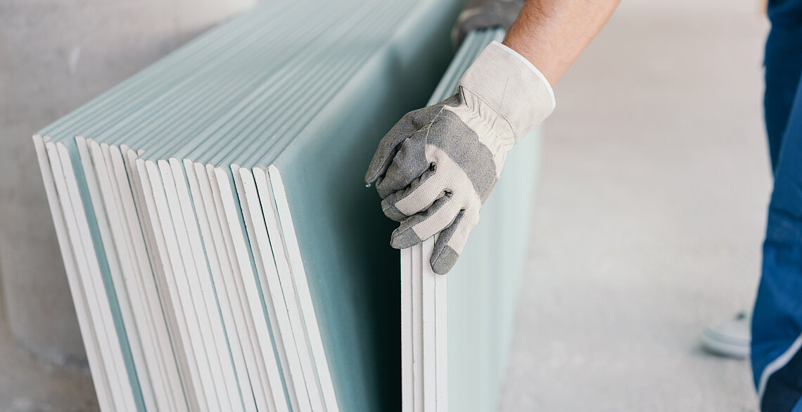 Bauarbeiter trägt Gipskartonplatten