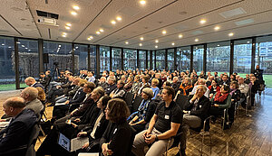 Viele Leute sitzen auf Stühlen in einem Raum